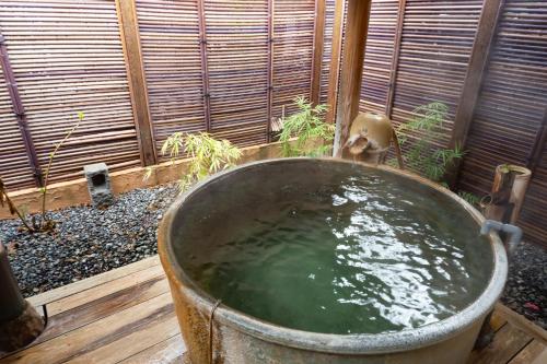 a large metal tub filled with water in a garden at Oyado Ichizen in Yufuin