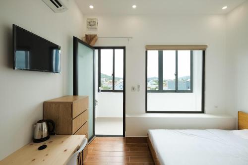 - une chambre avec un lit, un bureau et des fenêtres dans l'établissement Fisherman Homestay Phú Quốc - by Bay Luxury, à Duong Dong