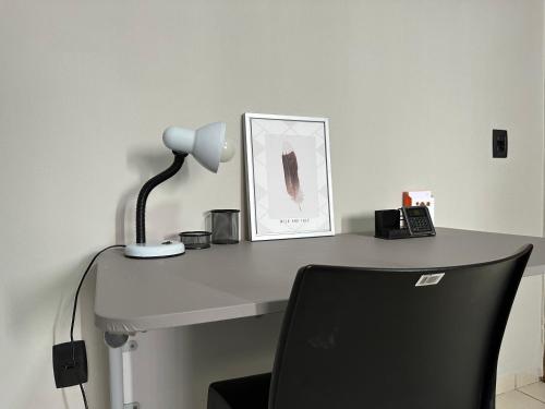 a desk with a lamp and a chair on it at VILINHA LOFT HOME AP- 02 - TÉRREO - Excelente Localização in Cuiabá
