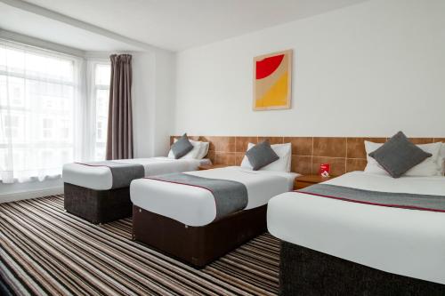 a hotel room with three beds and a window at Commercial Hotel in South Bank