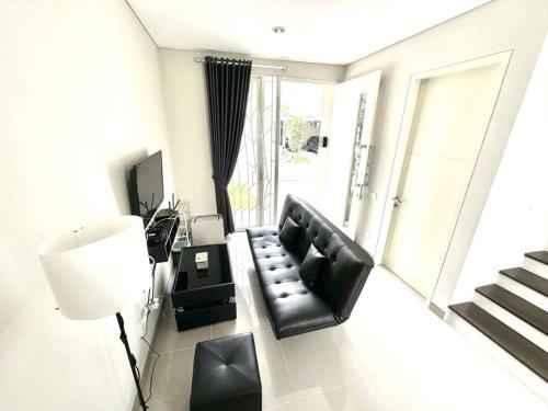 a living room with a black couch and a lamp at GreenLake Vista in Surabaya