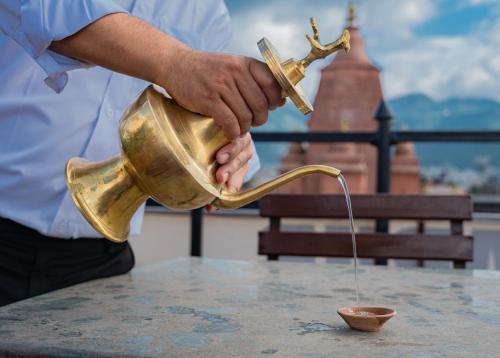 a man is pouring a drink into a copper tea pot at Sweet Home Bhaktapur in Bhaktapur