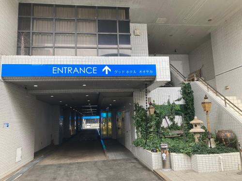 an entrance to a building with a blue sign on it at グッドホテル大阪 in Toyonaka