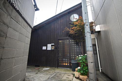 an alley with a black building with a gate at -時の宿 上七軒- Kyoto Machiya 金閣寺周辺 in Kyoto