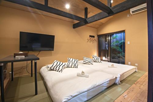 um quarto com 2 camas e uma televisão de ecrã plano em -時の宿 上七軒- Kyoto Machiya 金閣寺周辺 em Quioto