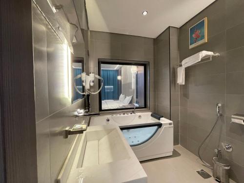 ein Badezimmer mit einer Badewanne, einem Waschbecken und einem Spiegel in der Unterkunft شاليهات راف in Chamis Muschait