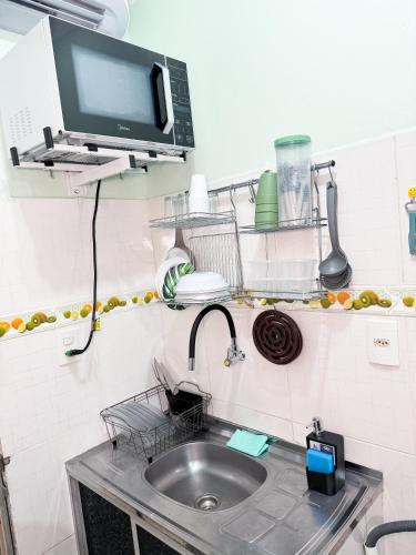 a kitchen with a sink and a tv on a shelf at Apartamento confortável mobiliado 03 in Manaus