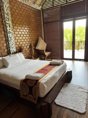 a bedroom with a large bed and a large window at OHEI in Tangalle
