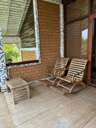two rocking chairs and a bench on a porch at OHEI in Tangalle