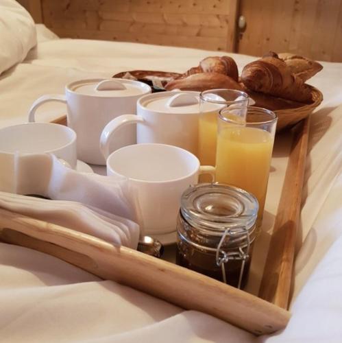 een dienblad met koffiekopjes en gebak op een bed bij Relais Mont Jura Adults Only in Lélex