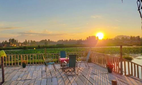 um deque com cadeiras e o pôr-do-sol ao fundo em Houseboat young wild Rose em Srinagar