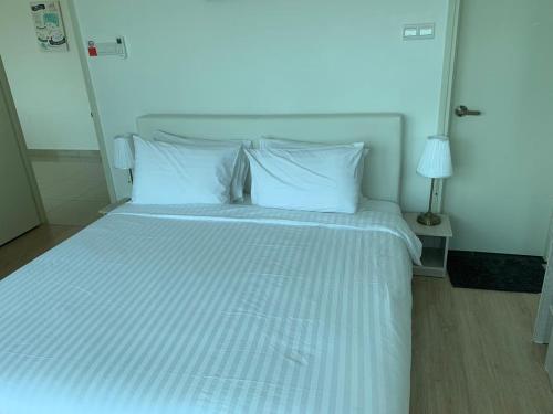 uma cama com lençóis brancos e almofadas num quarto em Arte Plus KLCC by PSM Luxury Suites em Kuala Lumpur