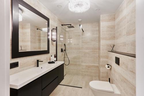 een badkamer met een wastafel, een toilet en een spiegel bij Azure Apartment - Playa Baltis in Międzyzdroje
