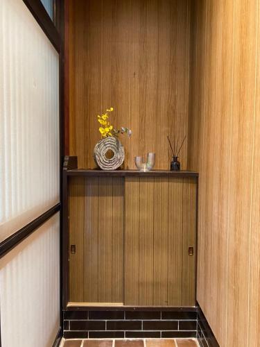 Un pasillo con un estante con un jarrón de flores. en Naoshima J-House, en Naoshima