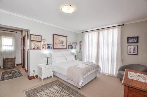 a bedroom with a white bed and a chair in it at NetReg in Yzerfontein