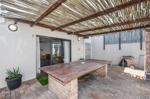 a patio with a wooden table on a brick patio at NetReg in Yzerfontein