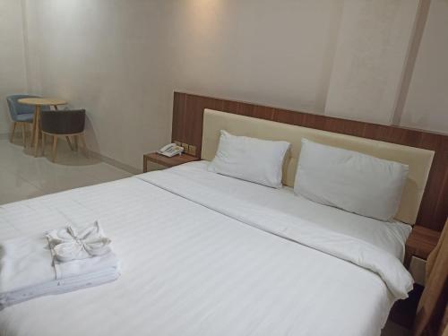 a bedroom with a white bed with a bow on it at Hotel Morena Batam in Batam Center