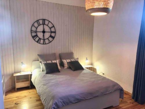 a bedroom with a large bed with a clock on the wall at Appartement 1 chambre terrasse 200m de la plage et GR34 in Saint-Lunaire