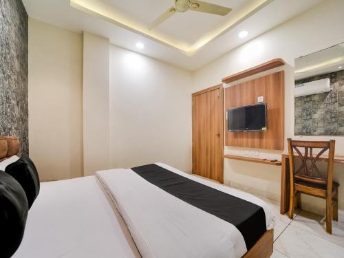 1 dormitorio con 1 cama, TV y silla en Collection O Zamzam Residency en Bhopal