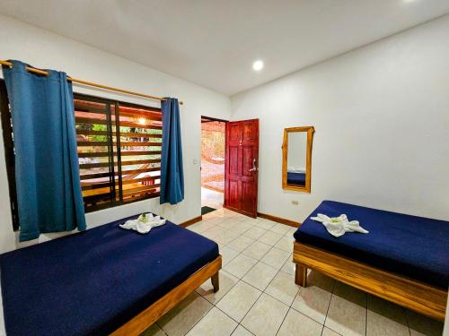 a bedroom with two beds and a window with blue sheets at Santa Toro in Santa Teresa Beach