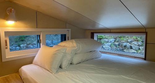 Starium Jecheon في Jecheon: سرير في غرفة صغيرة بها نافذتين
