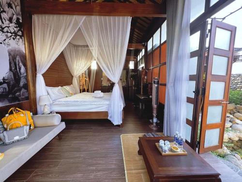 a bedroom with a bed with curtains and a table at Zen House Hoi An - Wooden House in Hoi An