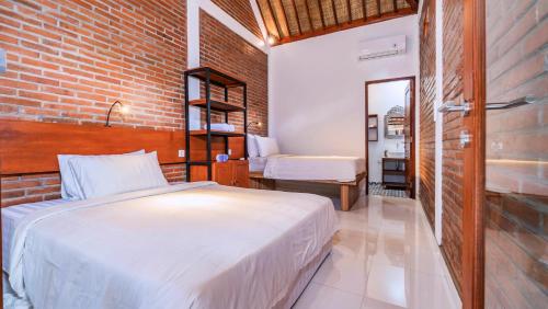 a bedroom with a bed and a brick wall at As I Am Ubud Retreat in Ubud