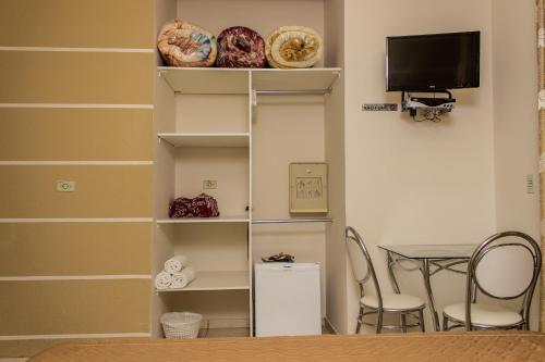 a room with a table and a shelf with a television at Pousada Cataratas in Foz do Iguaçu