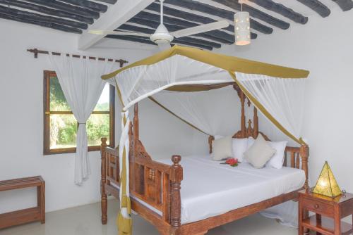 ein Schlafzimmer mit einem Himmelbett in der Unterkunft Pearl Beach by Sansi in Michamvi
