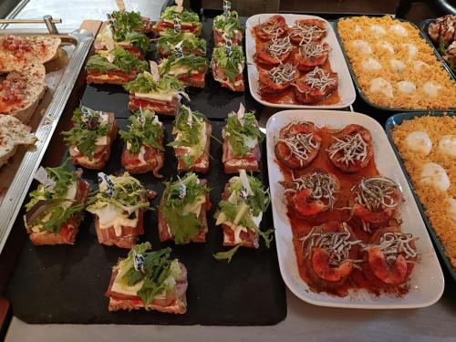 a table with several trays of sandwiches and other foods at Hotel Centro Los Braseros in Burgos