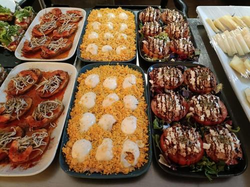 a table topped with trays filled with different types of food at Hotel Centro Los Braseros in Burgos