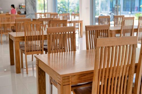 um grupo de mesas e cadeiras de madeira num restaurante em Hana Hotel Sonasea Night Market Phu Quoc em Duong Dong