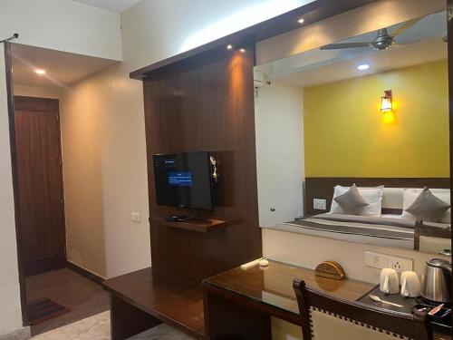a room with a bed and a desk with a television at Svaruchi Inn in New Delhi