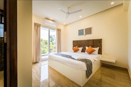 a bedroom with a bed and a large window at Luxury Apartments with Swimming Pool near Candolim Beach in Candolim