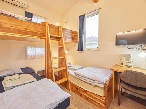 - une chambre avec des lits superposés, un bureau et des lits superposés dans l'établissement Itosima Guesthouse TOMO, à Itoshima