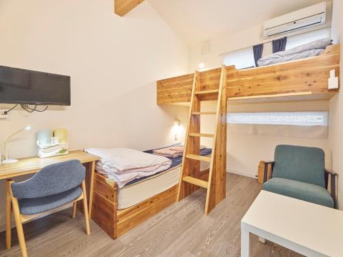 Pokój z łóżkiem piętrowym, biurkiem i krzesłami w obiekcie Itosima Guesthouse TOMO w mieście Itoshima