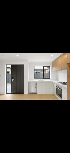 a kitchen with white cabinets and a black door at Hamilton New Town House in Hamilton