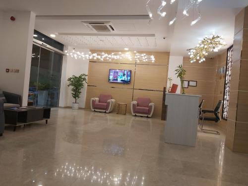 a lobby with pink chairs and a flat screen tv at Season Inn Hotel in Barka