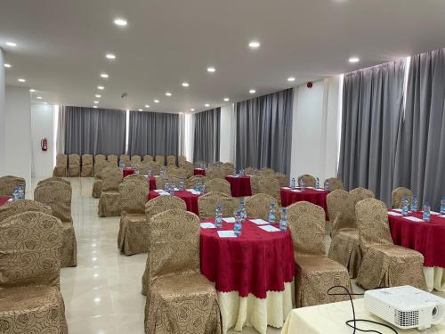 a banquet hall with tables and chairs with red table cloth at Season Inn Hotel in Barka