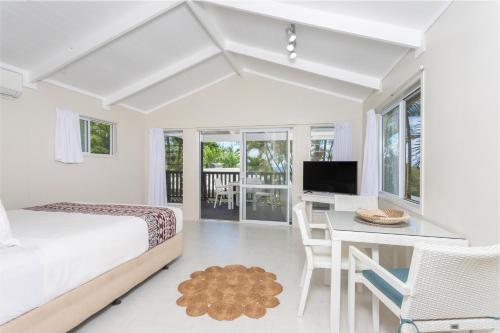 a bedroom with a bed and a desk and a television at Muri Lagoon View Bungalows - Hillside Bungalow in Rarotonga