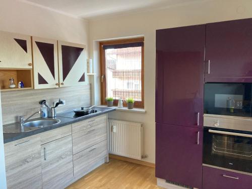 a kitchen with a sink and a purple refrigerator at Seeblick Faaker See in Drobollach am Faakersee