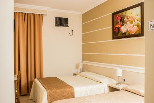 a hotel room with two beds and a painting on the wall at Pousada Cataratas in Foz do Iguaçu