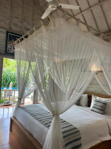 a bedroom with a canopy bed with white mosquito nets at 221 Garden Cottages in Nusa Lembongan