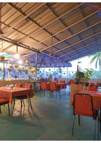 a restaurant with red tables and chairs and ceilings at Hotel Aramana in Kāladi