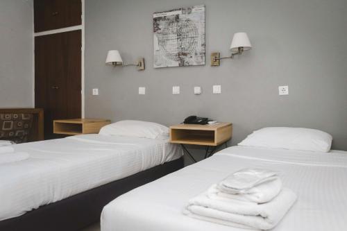 メッシーニにあるMessini Hotelのホテルルーム内のベッド2台(タオル付)