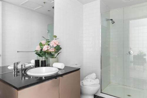 a bathroom with a sink and a toilet and a shower at A Stylish & Central 2BR Apt Near Flinders Station in Melbourne
