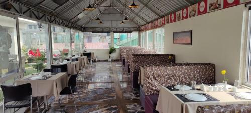 ein Esszimmer mit Tischen und Stühlen in einem Restaurant in der Unterkunft New Maya Residency in Darjeeling