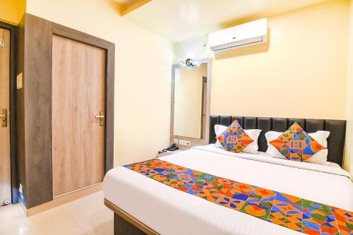 a bedroom with a large white bed with colorful pillows at FabHotel Bypass View in Kolkata