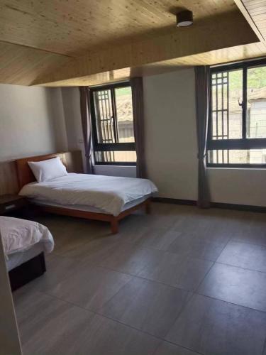 um quarto com 2 camas e 2 janelas em Beautiful Guest House II em Chin-sha