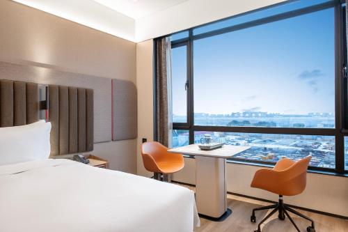 a hotel room with a bed and a desk and a window at IntercityHotel Shanghai Hongqiao Airport - Free Minibar for First Night in Shanghai